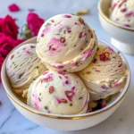 Close-up of vibrant scoops of Pistachio Rose Ice Cream, garnished with rose petals and pistachios in a gold-rimmed bowl.