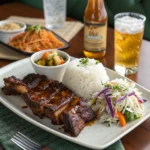 Garlic ribs served with rice, roasted vegetables, and coleslaw, paired with iced tea