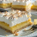 A close-up of Lemon Meringue Pie Bars showing the thick lemon filling and airy meringue topping.