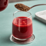 Spoonful of black chia seeds over a glass of beetroot detox drink