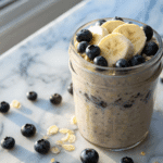 Blueberry banana overnight oats in a glass jar topped with banana slices and fresh blueberries