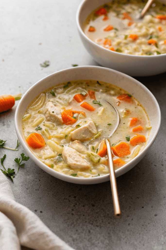 lemon chicken orzo soup with carrots and chicken chunks in a bowl