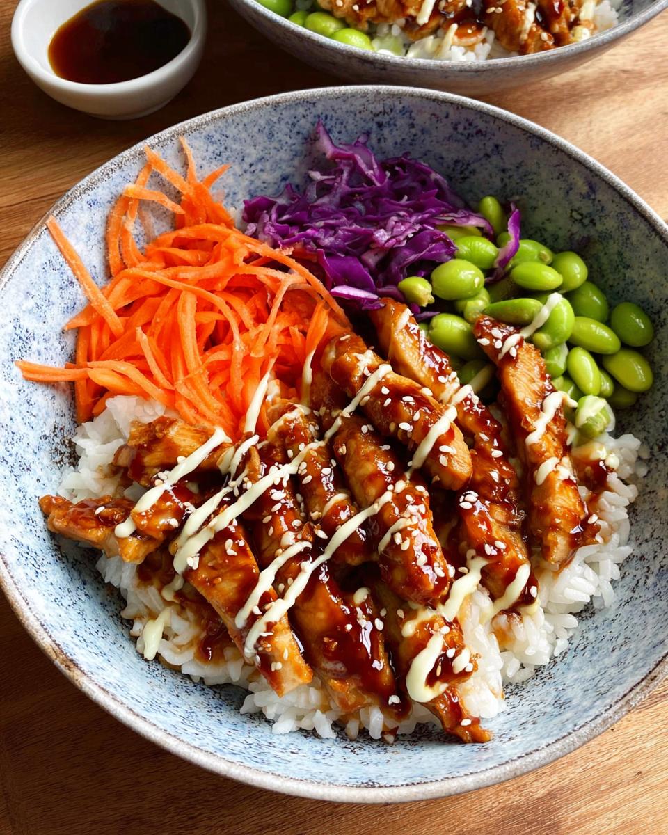 Close-up of a 15-Minute Teriyaki Chicken Bowl with rice, teriyaki chicken, shredded carrots, edamame, and red cabbage.