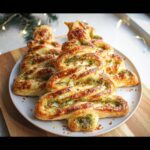 A golden-brown Basil Pesto Puff Pastry Christmas Tree, filled with green pesto and cheese, sprinkled with red pepper flakes.