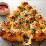 A golden-brown Cheesy Pull-Apart Christmas Tree Bread with melted cheese stretching from a pulled-apart piece.