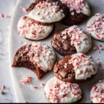 A close-up of several Chocolate Peppermint Bark Cookies, featuring a dark chocolate cookie base dipped in white chocolate and topped with crushed peppermint candy.