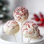 Close-up of Classic Christmas Cake Pops dipped in white chocolate and decorated with red, green, and white sprinkles.
