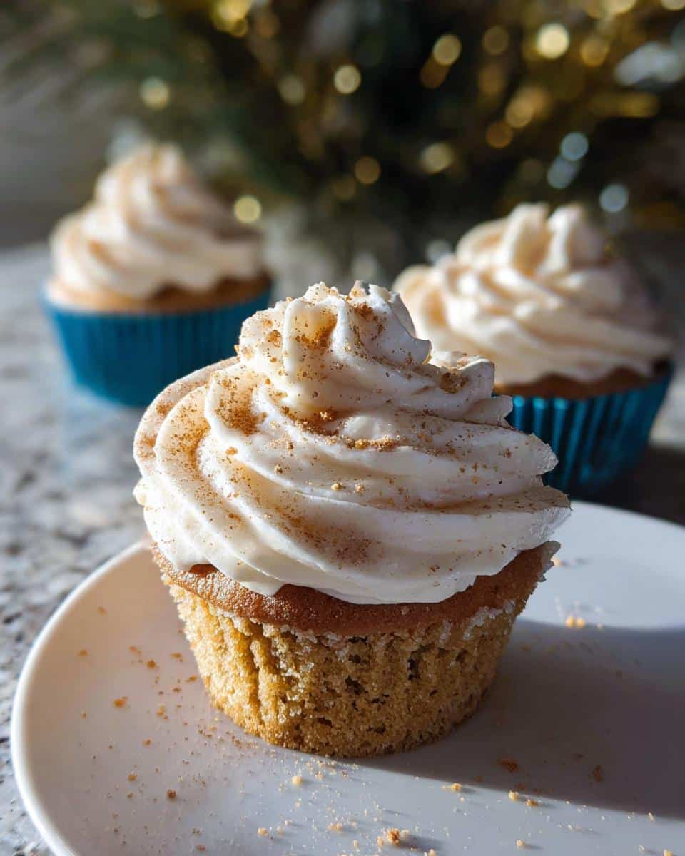 Close-up of an Eggnog Cupcake with Cream Cheese Frosting, dusted with cinnamon.