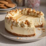 A slice of creamy Gingerbread White Chocolate Cheesecake topped with whipped cream and gingerbread crumbs.