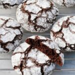 Close-up of delicious Gluten-Free Chocolate Crinkle Cookies dusted with powdered sugar on a cooling rack.