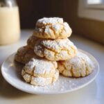 A stack of Gluten-Free Gooey Butter Cookies dusted with powdered sugar on a white plate.