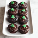 A plate of delicious Gluten-Free Holiday Brownie Bites topped with festive green Christmas tree frosting and red sprinkles.