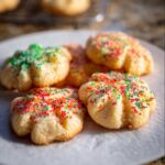 Close-up of festive Gluten-Free Spritz Cookies topped with colorful sprinkles on a white plate.