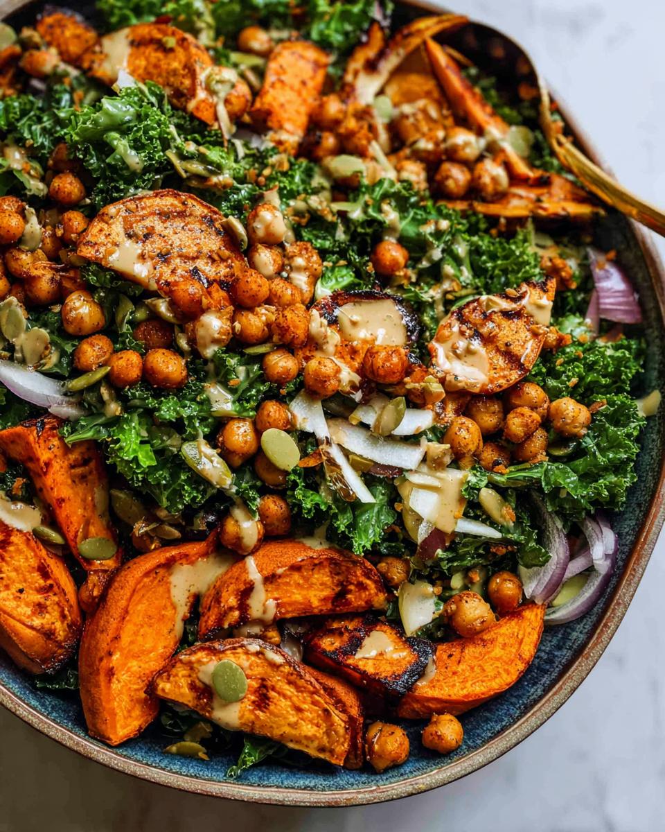 A vibrant and colorful Kale & Sweet Potato Harvest Bowl, featuring roasted sweet potato wedges, crispy chickpeas, and fresh kale, drizzled with tahini dressing.