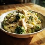 A bowl of creamy Low-Carb Chicken Broccoli Alfredo Crockpot topped with shredded cheese.