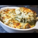 A fork lifting a cheesy serving of Low Carb Pesto Chicken Bake, showing melted mozzarella and pesto.