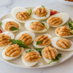 Mini Pumpkin Deviled Eggs decorated with paprika and parsley, served on a platter as a festive fall appetizer