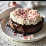A rich chocolate Peppermint Bark Cheesecake topped with whipped cream and crushed candy canes.