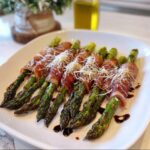 Close-up of Prosciutto-Wrapped Asparagus Bundles topped with shredded Parmesan cheese and drizzled with balsamic glaze.