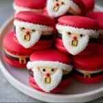 Close-up of adorable Santa Claus Macarons with red shells, white coconut beards, and gold buckles.