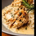 Close-up of tender Slow Cooker Lemon Herb Chicken & Rice, drizzled with creamy sauce and garnished with rosemary.