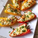 Close-up of Stuffed Mini Peppers with Herbed Cheese, baked until golden and sprinkled with fresh parsley and sesame seeds.