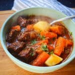 A close-up of a steaming bowl of Whole30 Beef & Vegetable Stew with tender beef chunks, carrots, and potatoes.