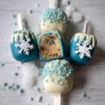 Close-up of Winter Wonderland Cake Pops decorated with blue and white icing, snowflakes, and blue sugar crystals.