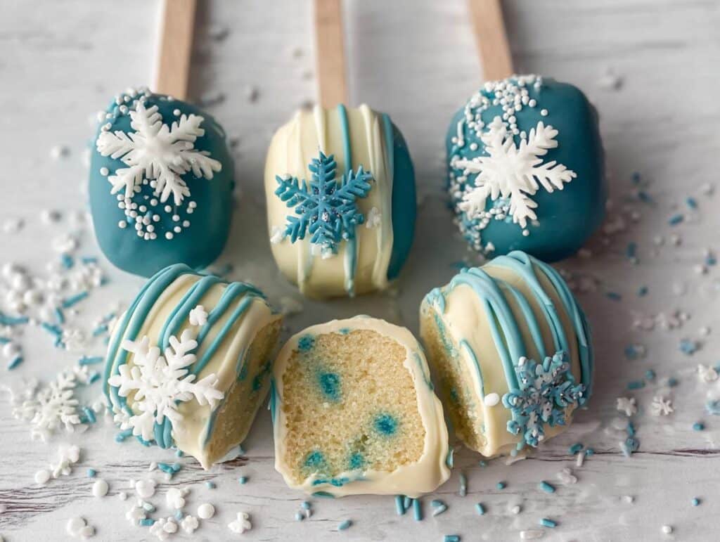 Close-up of festive Winter Wonderland Cake Pops decorated with white and blue snowflakes and sprinkles.