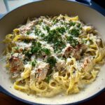 Close-up of Alfredo Protein Pasta Bowls featuring fettuccine, grilled chicken pieces, grated Parmesan, and fresh parsley.
