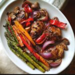 A platter of Balsamic Chicken with Roasted Veggies including asparagus, carrots, red peppers, red onion, and mushrooms.