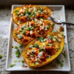 Three halves of Buffalo Chicken Spaghetti Squash filled with shredded chicken, cheese, and blue cheese crumbles, drizzled with sauce.