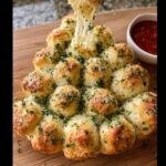 A hand pulling apart a cheesy section of the Christmas Tree Pull-Apart Bread, showing melted cheese strings.