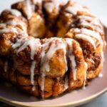 Close-up of a round Cinnamon Roll Monkey Bread, generously drizzled with white icing.