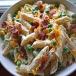 Close-up of creamy penne pasta mixed with peas, bacon bits, and shredded cheddar, part of the 20g Protein Greek Yogurt Pasta Bowls.