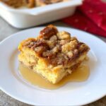A slice of Eggnog French Toast Casserole served on a white plate with syrup.