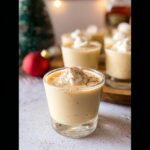 Close-up of creamy Eggnog Pudding Jello Shots topped with whipped cream and cinnamon.