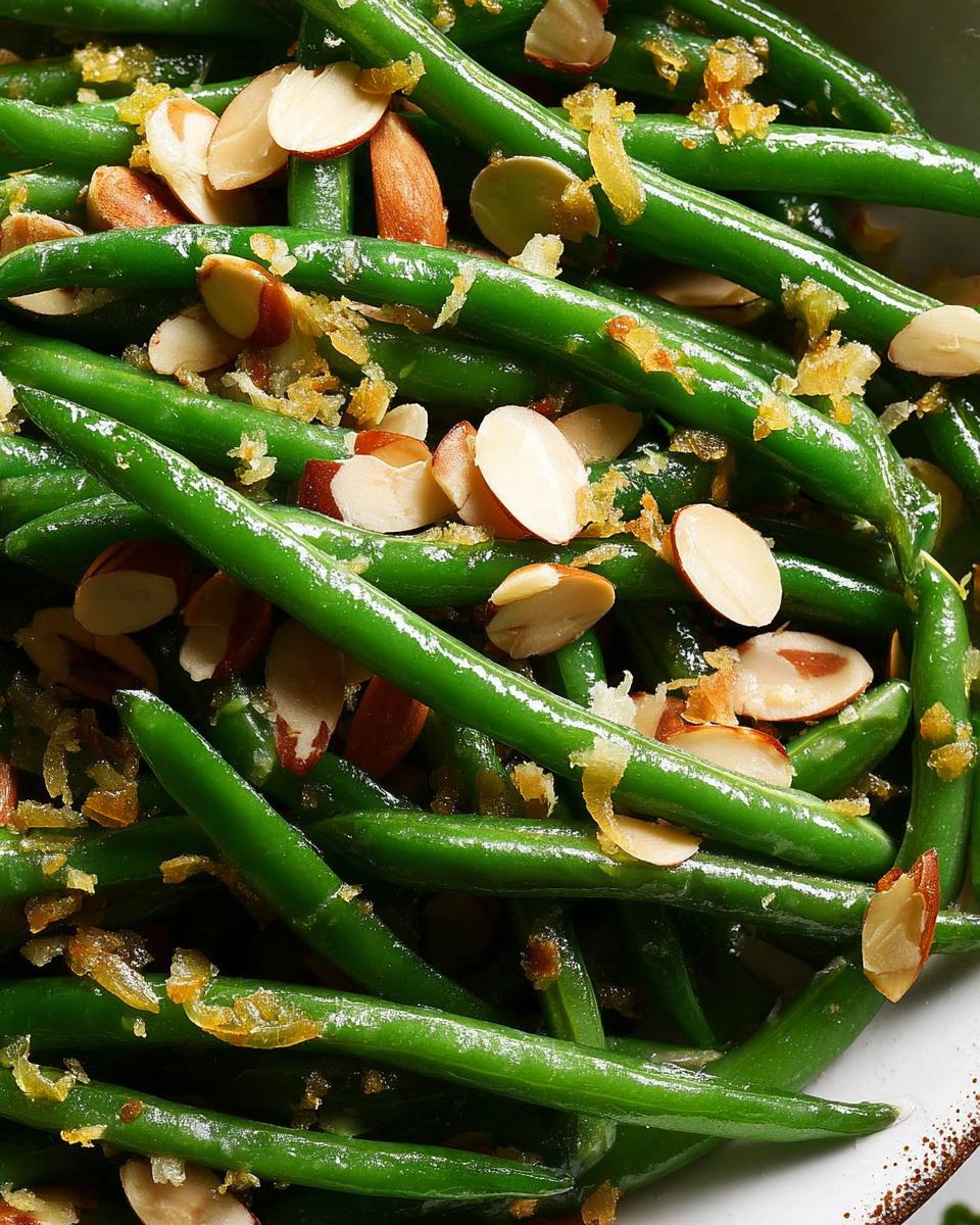 Close-up of bright green beans tossed with sliced almonds and browned butter for Holiday Green Bean Almondine.