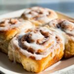 Close-up of freshly baked Maple Cinnamon Breakfast Rollups generously topped with white glaze icing.