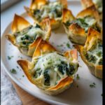 Close-up of baked Mini Spinach & Artichoke Wonton Cups topped with melted, gooey cheese and parsley.