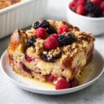 A delicious slice of Mixed Berry French Toast Bake topped with fresh berries and streusel.