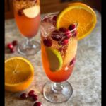 Close-up of a refreshing Orange Cranberry Sangria Mocktail with orange slice, cranberries, apple slices, and ice.