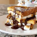 Close-up of stacked S’mores French Toast dripping with melted chocolate and toasted marshmallows.