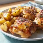 Close-up of juicy Spicy Honey-Lime Chicken Thighs served with golden roasted potatoes, garnished with herbs.