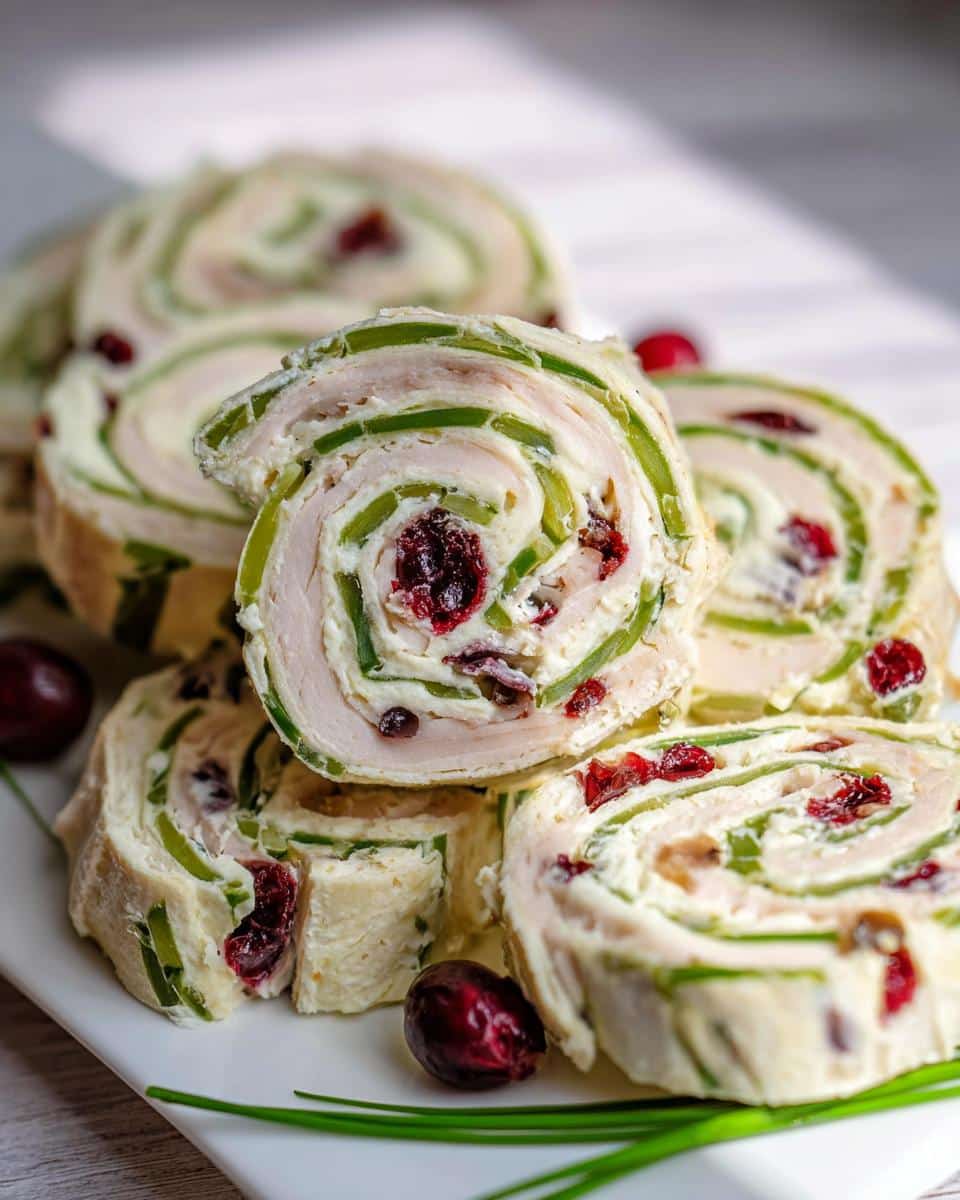 Close-up of sliced Turkey & Cranberry Pinwheels showing layers of turkey, cream cheese, green onions, and dried cranberries.