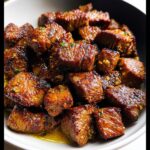 A bowl filled with perfectly seared, juicy cubes of 30-Minute Garlic Butter Steak Bites coated in a rich, glistening garlic butter sauce.