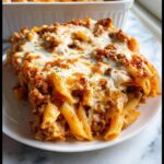 A generous serving of Cheesy Ground Beef & Pasta Bake featuring penne pasta, rich meat sauce, and a thick layer of melted mozzarella cheese.