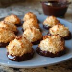 A plate of freshly baked Coconut Macaroon Cookies, toasted golden brown and dipped in melted dark chocolate.