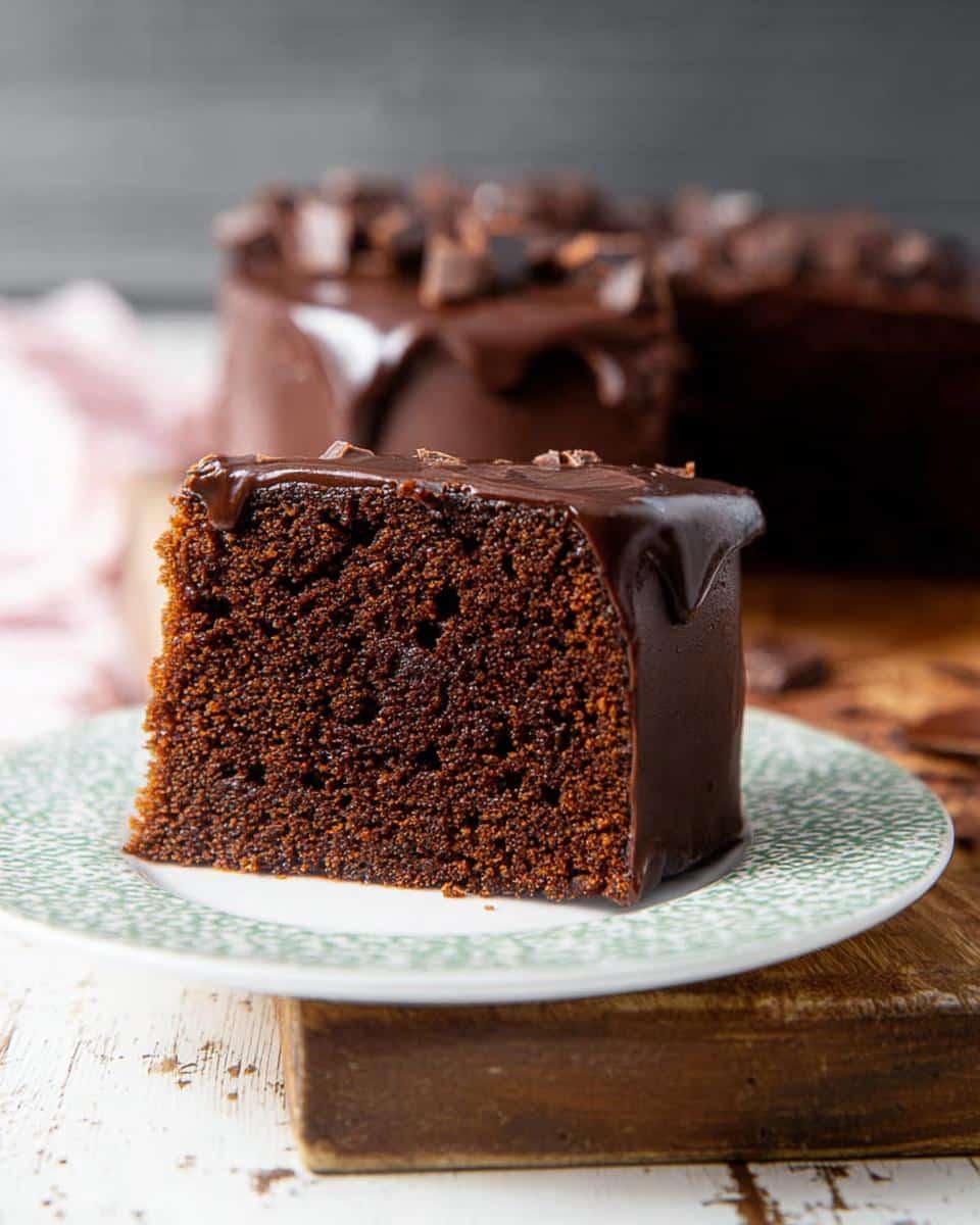 A close-up of a rich slice of Chocolate Mud Thermomix Cake topped with dripping chocolate ganache.