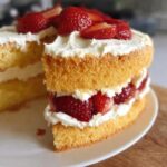 A thick slice of fluffy Classic Thermomix Sponge Cake layered with whipped cream and fresh strawberries.